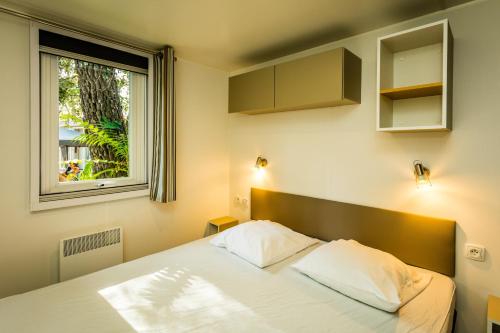 a bedroom with a bed and a window at Camping la Sousta**** in Remoulins