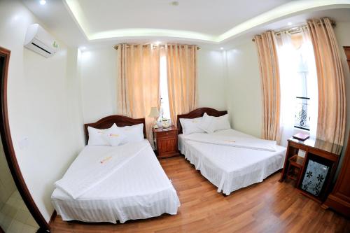 1 dormitorio con 2 camas, sábanas blancas y suelo de madera. en Thuan Thanh Hotel, en Ninh Binh