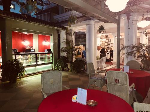 a restaurant with red tables and chairs and a counter at The Elgin Fairlawn, Kolkata in Kolkata
