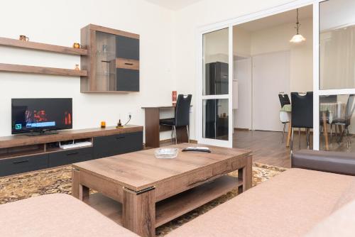 Central Academic Apartment Sofia في صوفيا: غرفة معيشة مع طاولة خشبية وتلفزيون