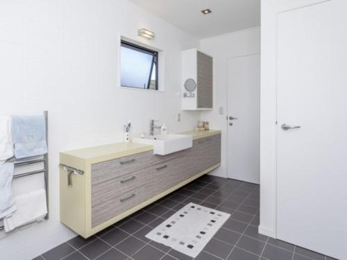 a white bathroom with a sink and a mirror at Hahei Beach Apartment in Hahei