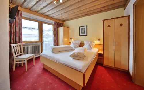 a bedroom with a bed with a chair and a window at Haus Oberacher in Serfaus