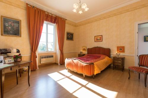 a bedroom with a bed and a desk and a window at Chambres d'Hôtes du Chalet de Caharet in Pipriac