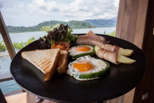 a plate of breakfast food with eggs sausage and bread at Parama Koh Chang in Ko Chang