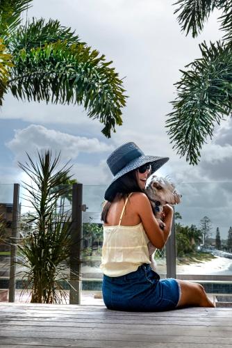 a woman sitting on a dock holding a dog at Saltwater Villas - Pet Friendly Accommodation in Mooloolaba