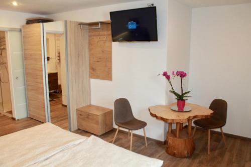 een kamer met een tafel en stoelen en een tv aan de muur bij Echt Heimat Apartments in Sankt Gilgen