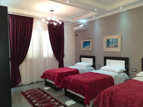 Hotel Erandi في Rinas: غرفة نوم بسريرين مع شراشف حمراء ونافذة