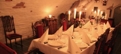 une grande table avec des nappes blanches et des bougies dans l'établissement Brunsbo G:a Biskopsgård Hotell & Konferens, à Skara