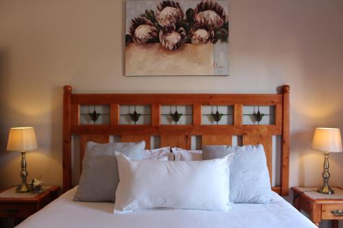 una camera con letto in legno e cuscini bianchi di Feathers Guest House a Middelburg