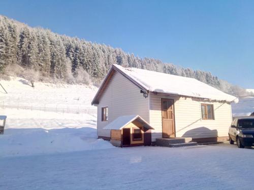 una pequeña casa blanca con nieve encima en Відпочинок у Карпатах en Volovets