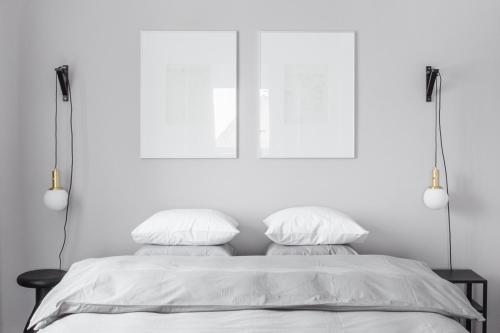 a white bedroom with a bed with two white pillows at Minimalist. Apartment & Studio in Šiauliai