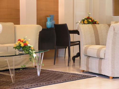 a living room with chairs and a table with flowers on it at Aparthotel England in Riccione