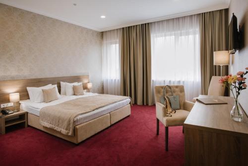 ein Hotelzimmer mit einem Bett und einem Stuhl in der Unterkunft Hotel Alkor in Truskawez