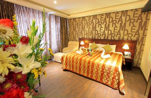 um quarto de hotel com uma cama e flores em Hotel All Season em Coulão