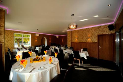 a dining room with white tables and chairs at Hotel zur Heideblüte in Hambühren