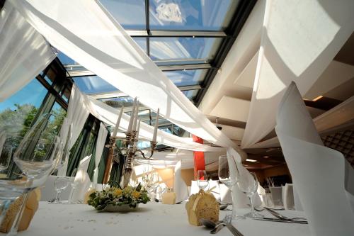 a room with a table with white curtains and flowers at Hotel zur Heideblüte in Hambühren