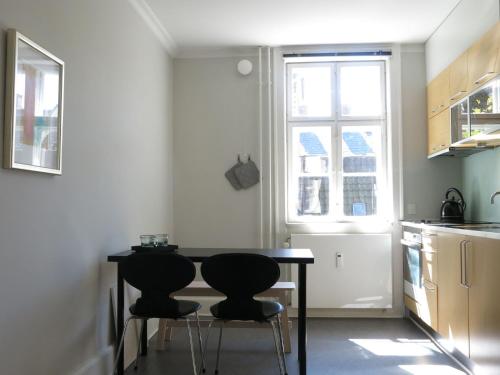 uma cozinha com uma mesa preta e duas cadeiras em ApartmentInCopenhagen Apartment 1143 em Copenhague