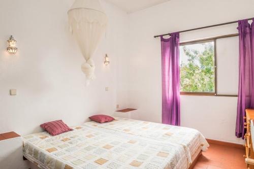 タヴィラにあるAlmargem 42のベッドルーム1室(紫色のカーテンと窓付きのベッド1台付)