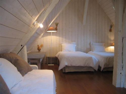 une chambre avec deux lits et une table avec une lampe dans l'établissement La Ferme au colombier, à NÃ©ron