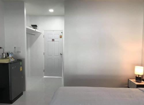 ein Schlafzimmer mit einem Bett und einer weißen Wand in der Unterkunft Airport Pearl Residence in Nai Yang Beach