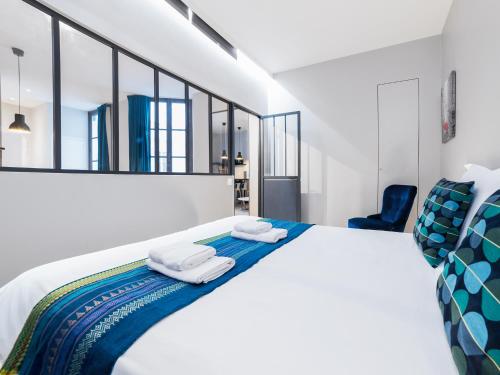 une chambre avec un grand lit blanc avec des serviettes dessus dans l'établissement Chic Apartments Opera, à Paris