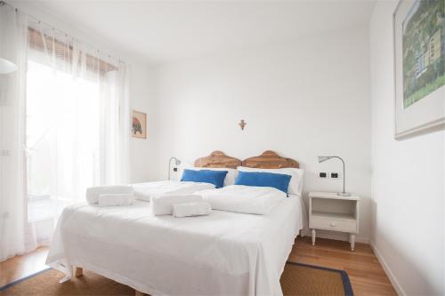 a white bedroom with a large white bed with blue pillows at Casa Davide in Riva del Garda