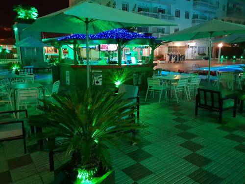 a restaurant with tables and chairs and umbrellas at night at Europa Family Apartments in Blanes