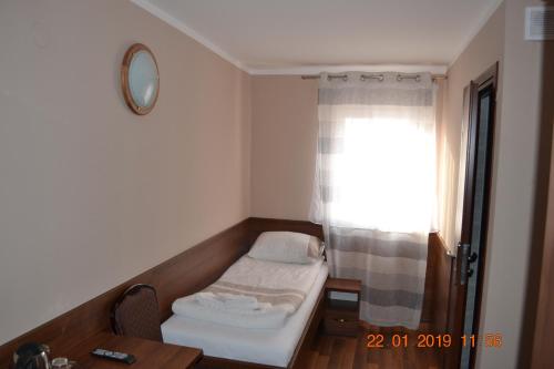 a small room with a bed and a window at Hotelik Karter in Warsaw