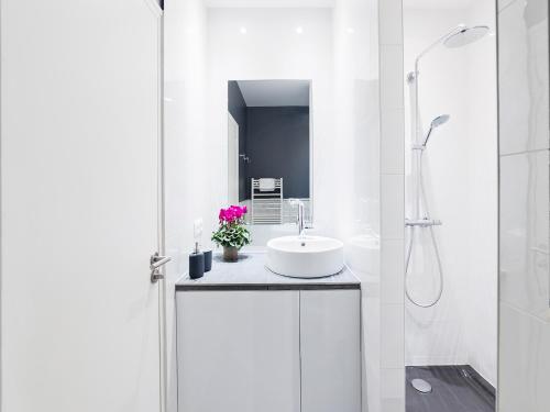 une salle de bain blanche avec un lavabo et une douche dans l'établissement Chic Apartments Opera, à Paris