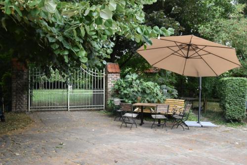 a table and chairs with an umbrella next to a fence at B&B Het Loonderhof in Borgloon
