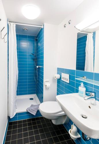 a blue tiled bathroom with a toilet and a sink at Jugendherberge Lenggries in Lenggries