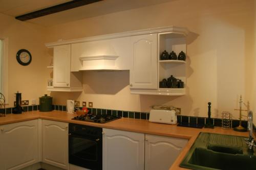 a kitchen with white cabinets and a stove top oven at Embleton Spa Hotel & Apartments in Embleton