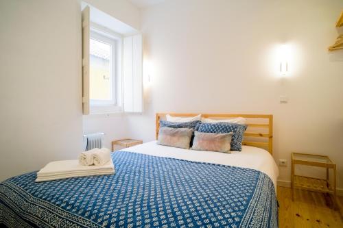 a bedroom with a bed with a blue comforter and a window at Bright And Sunny Apartment in Lisbon