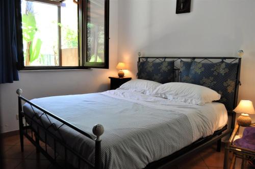 a bedroom with a bed with white sheets and a window at Casa Mia 6 posti letto con giardino in San Vito lo Capo