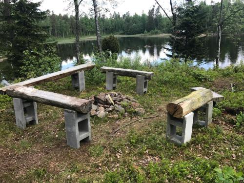 two wooden benches sitting next to a lake at Sävekulla 207 "Brygghuset" in Älvsered