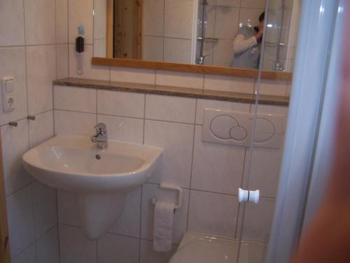 una persona que toma una foto de un baño con lavabo en Bungalow Ungers Welt 1 en Ostseebad Nienhagen