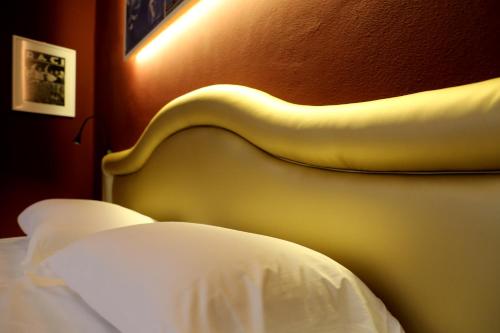 a bedroom with a white bed with a yellow headboard at OFFICINA TESINI Guest Rooms Verona in Verona