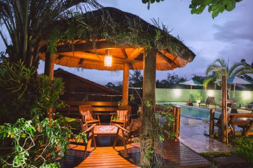a patio with a table and chairs under a large umbrella at Pousada Cabanas Kaia Lua in Praia do Rosa