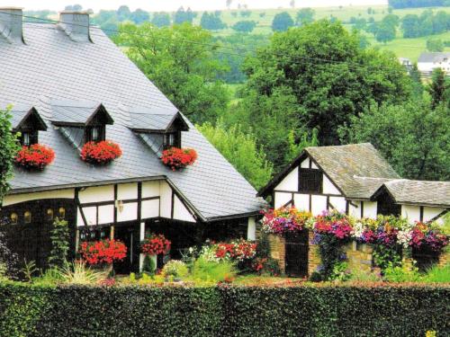 a house with flowers in the windows of it at Cozy Cottage in Malmedy with Large Garden in Malmedy