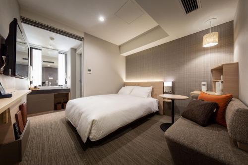 pokój hotelowy z łóżkiem i kanapą w obiekcie Nishitetsu Hotel Croom Nagoya w mieście Nagoja