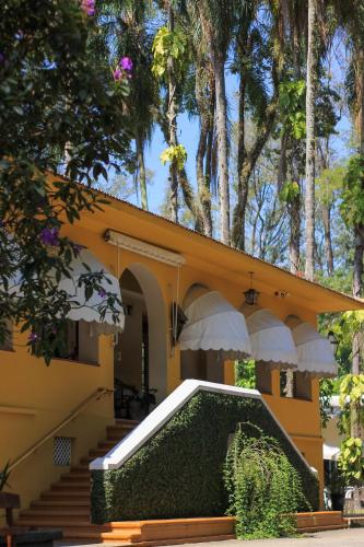 a yellow house with stairs and a porch with trees at Hotel Resort e Golfe Clube dos 500 in Guaratinguetá