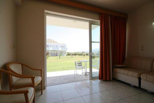 a living room with a couch and a sliding glass door at Zorbas Beach Hotel in Tigaki