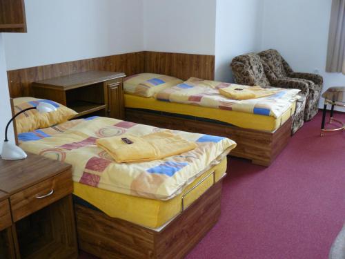 a room with two beds and a chair at Koleje Zamecek in Lednice
