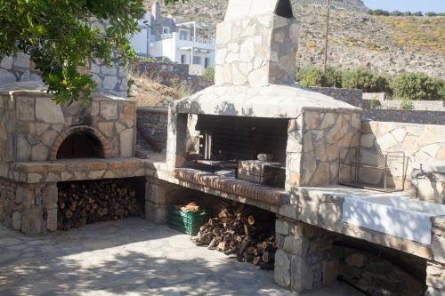 an outdoor pizza oven with a pile of fire wood at Krinakia Villas in Xerokampos