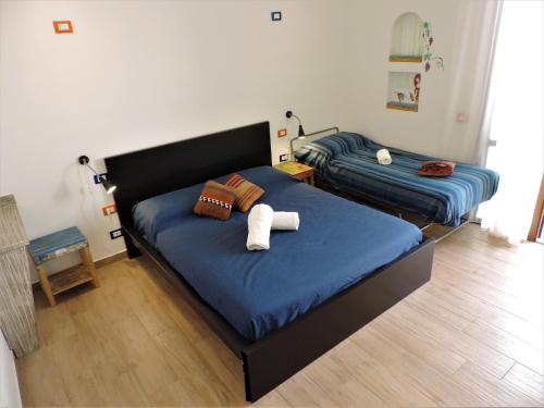 two beds in a bedroom with blue sheets at Timbuktu Hostel in San Vito lo Capo
