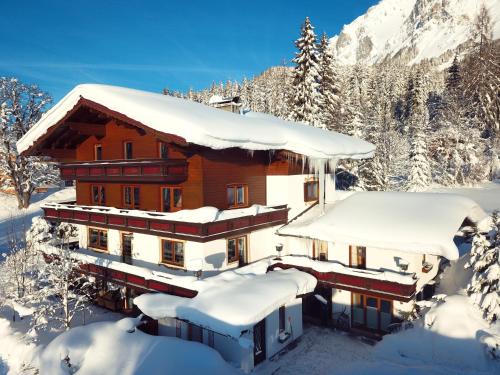 une maison recouverte de neige dans les montagnes dans l'établissement Pension Dachsteinhof, à Ramsau am Dachstein