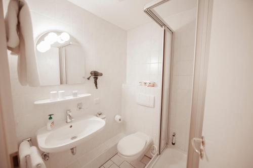 a white bathroom with a sink and a toilet at Le Anfore in Bad Windsheim