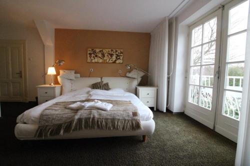 a bedroom with a large bed and two windows at Villa Wambach in Tegelen