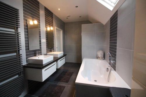 a bathroom with two sinks and a bath tub at Villa Wambach in Tegelen
