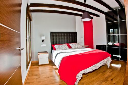 a bedroom with a red bed with a black headboard at Apartamentos El Roble in Valverde de la Vera